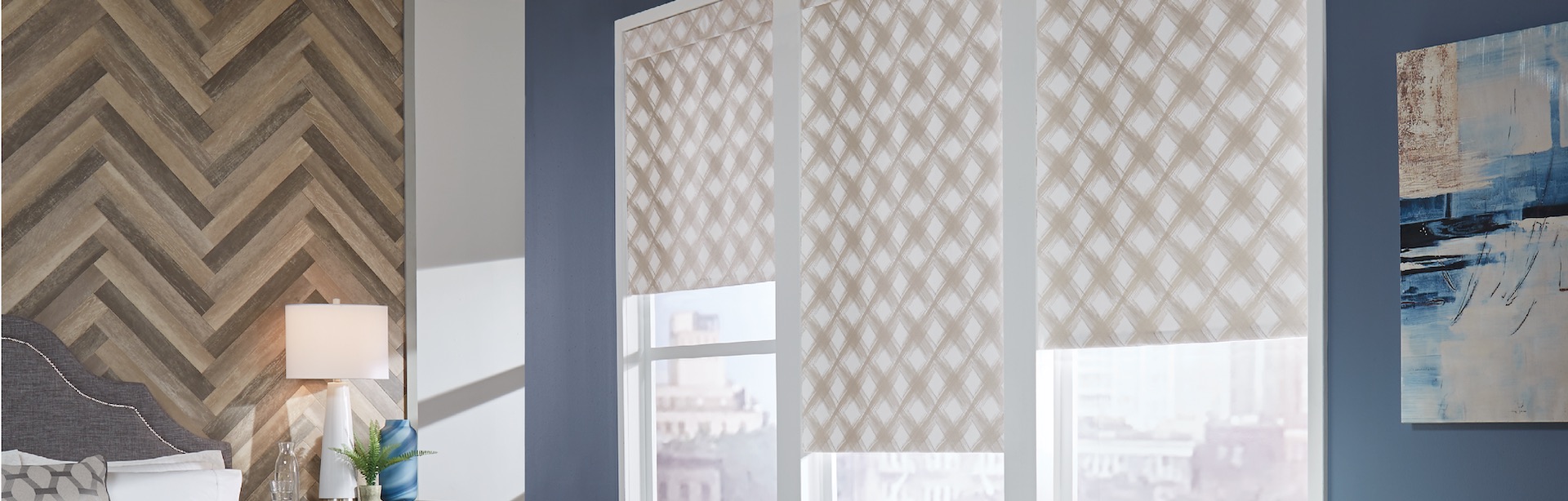 Slider images-Roller Shade Light neutral print fabric roller shades from Carole Fabrics, half open to overlook downtown, in a medium blue bedroom.
