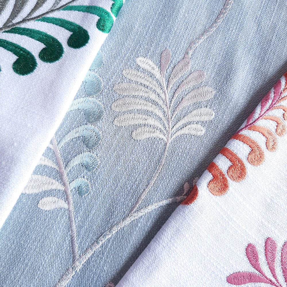 Decorative fabrics embroidered with leaf patterns in greens and pinks.