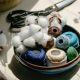 A bowl of yarn and cotton bolls on a cloth-covered surface.