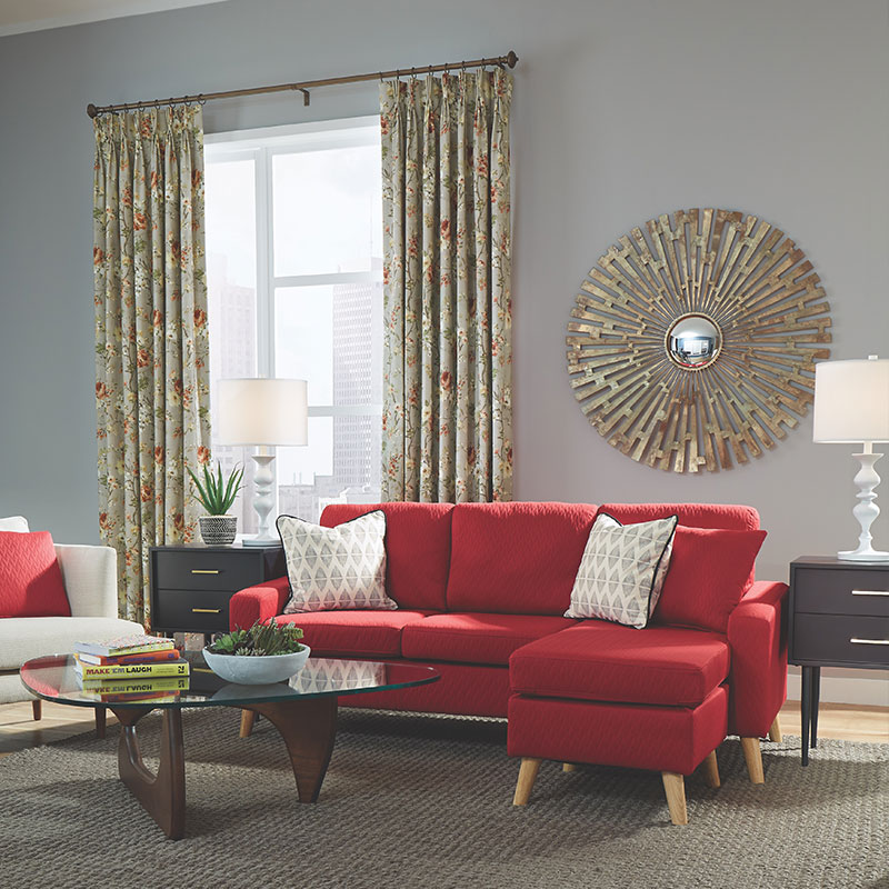 Neutral floral draperies with red accents in a living room with a red sofa.