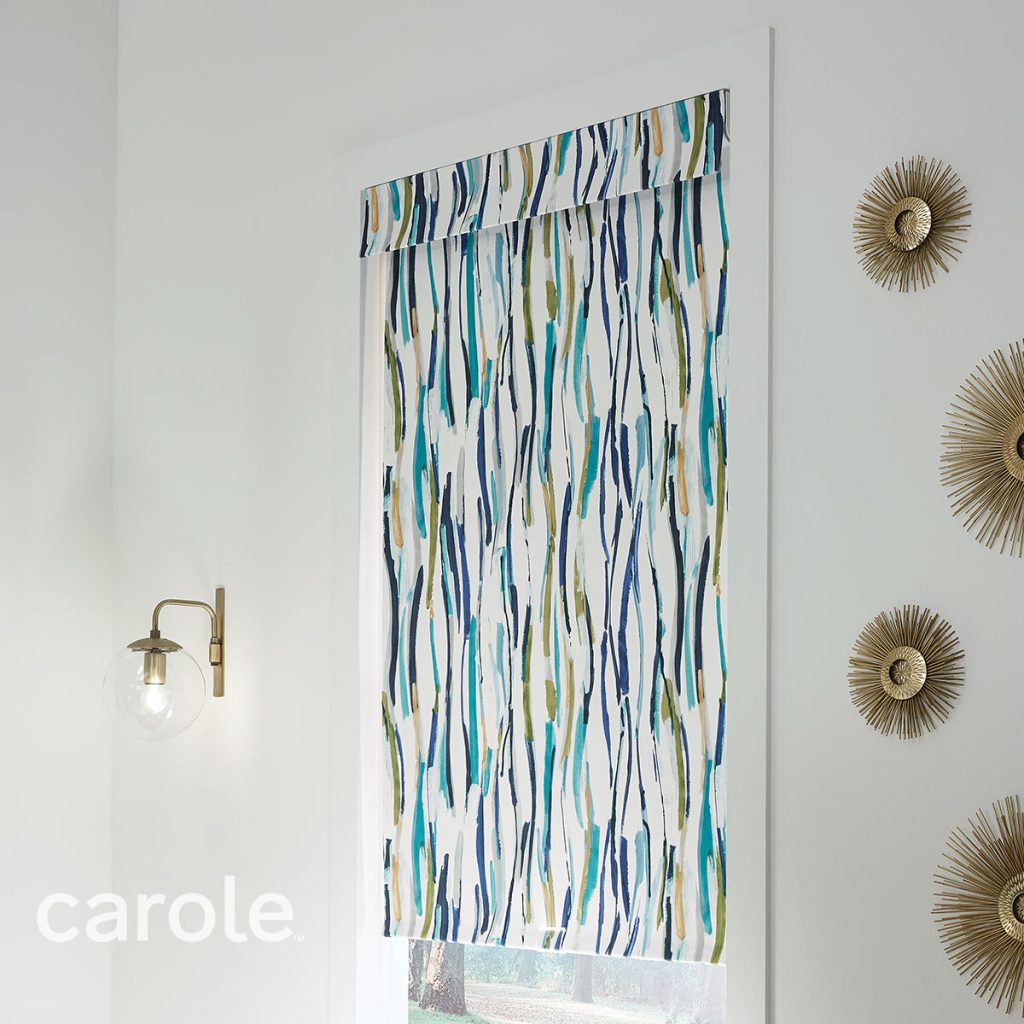 Angled view of a Standard Roll Inside Mount Decorative Fabric Roller Shade and a Courtesy Valance with an abstract print in a white room.