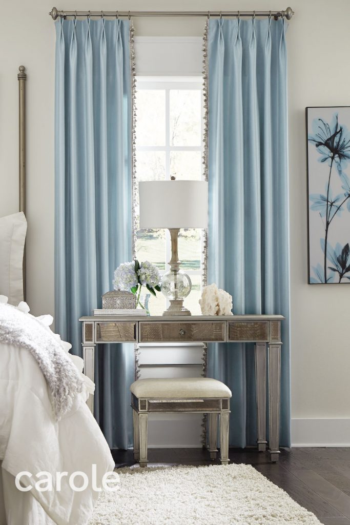 Light blue Monarch Pleat Drapery with Vertical Tassel Fringe Trimming in a white and silver bedroom.