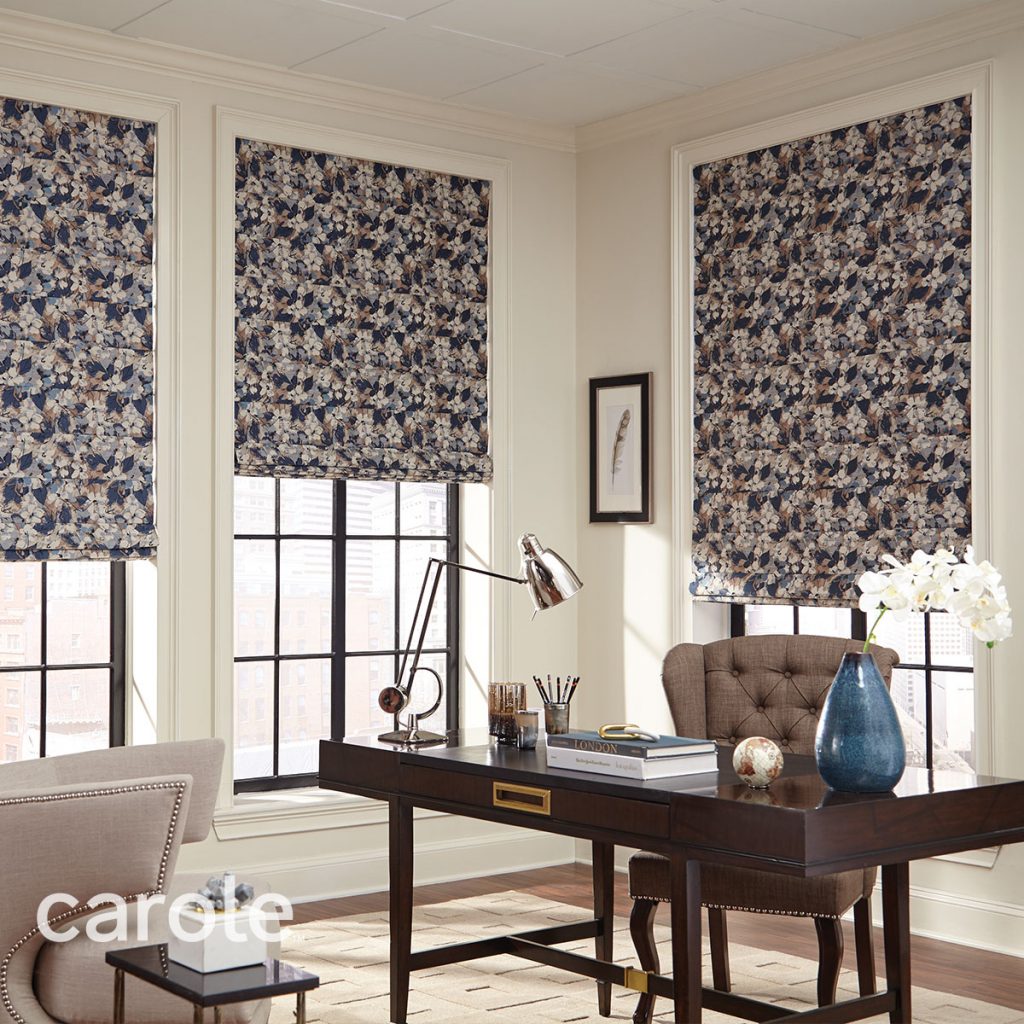 A warm neutral corner office with Reverse Fold Roman Shades in a dark blue and beige all over floral pattern.