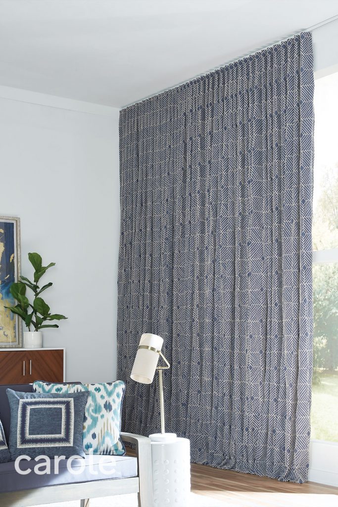 Ripplefold Drapery with a subtle navy blue and off-white geometric pattern on floor to ceiling windows in a living room.