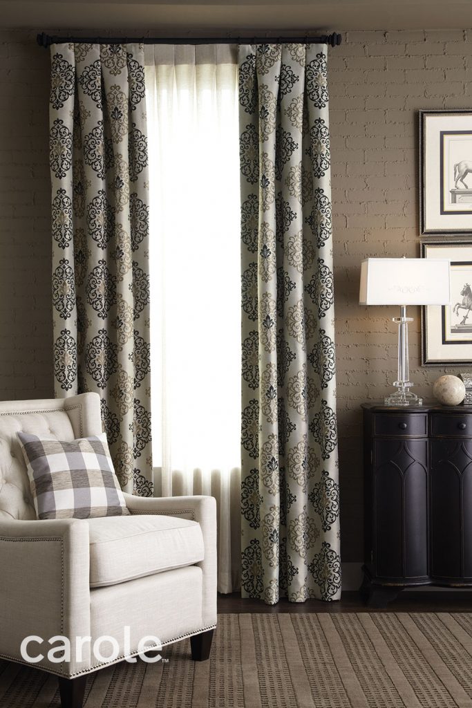 Tuxedo Pleat Drapery with a large scale pattern in light and dark neutrals over Sheer Tuxedo Pleat Drapery in a dark neutral sitting area.