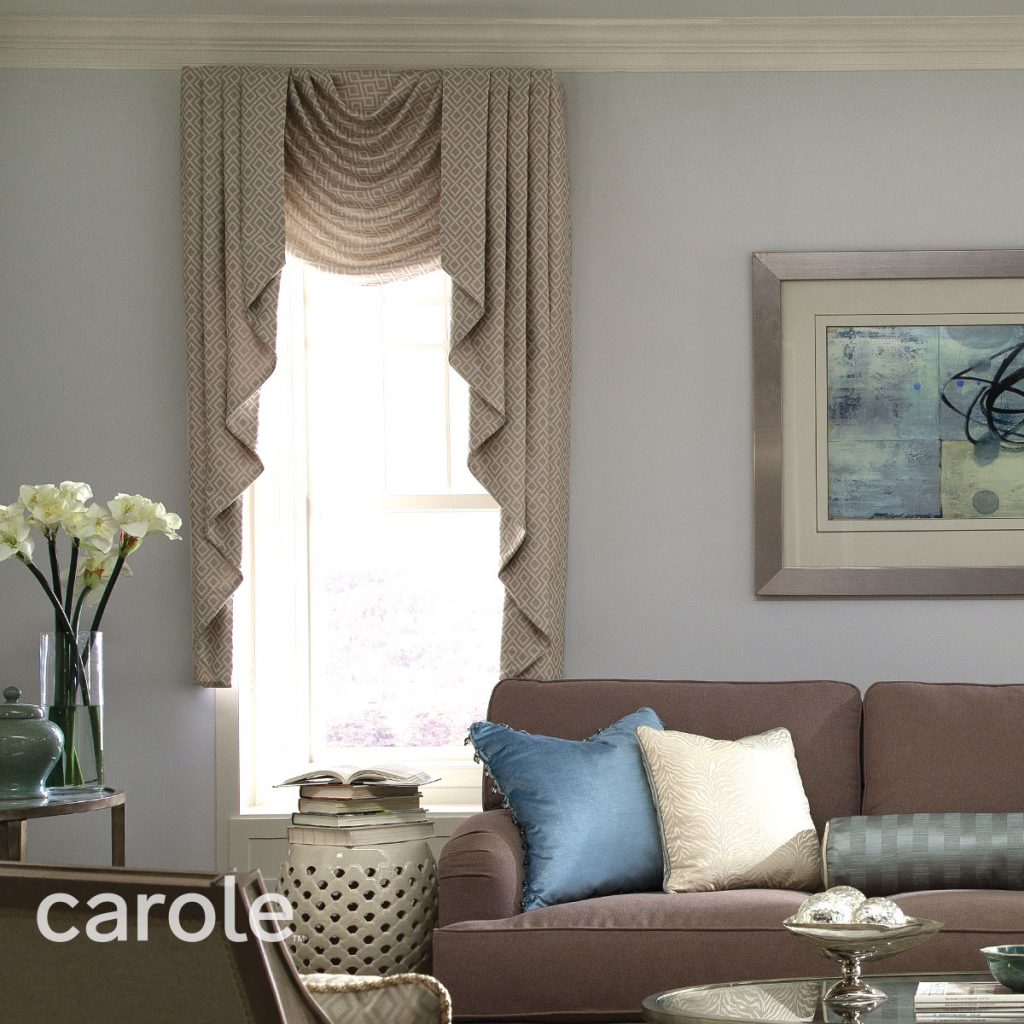 Astor Swag top treatment on a bright window in a neutral colored living room.