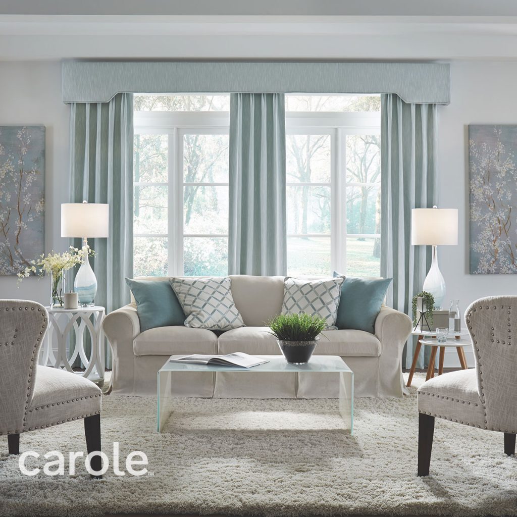 Pale blue Belvedere Cornice top treatment and Pleated Drapery over a wall of windows in a light neutral living room.