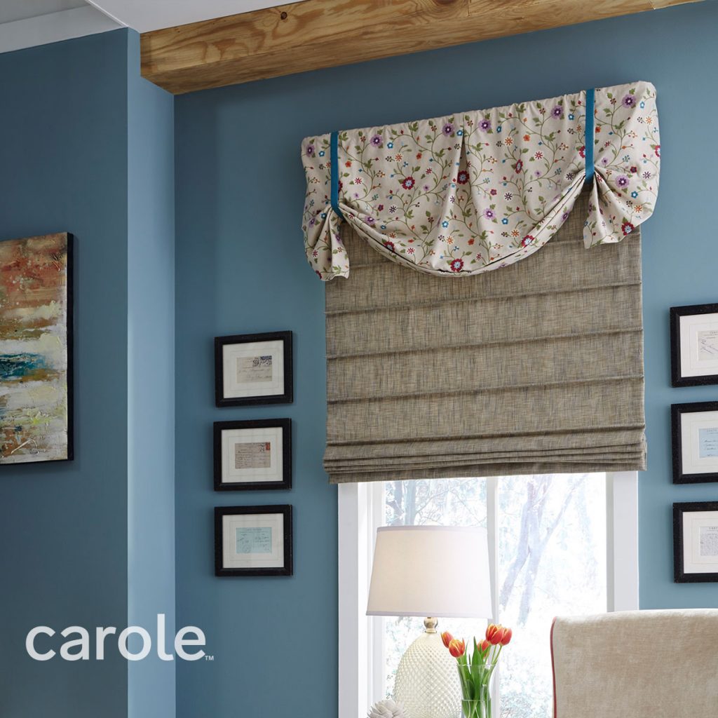 Floral-patterned Danby Rod Mounted Valance top treatment over a beige Front Fold Roman Shade in a blue room.
