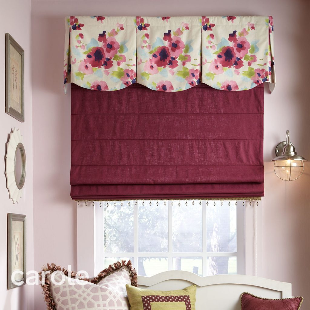 Summerton Rod Mounted Valance top treatment with a large scale floral pattern over a maroon Reverse Fold Roman Shade with beaded trim in a pink walled room.