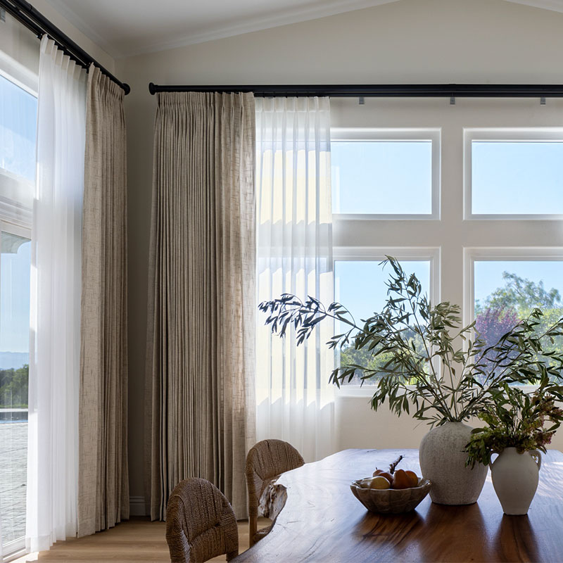 Large dining room windows with a double layer of drapery on 1 3/8" and 2" Estate Traverse Rods from Kirsch Drapery Hardware in Black.