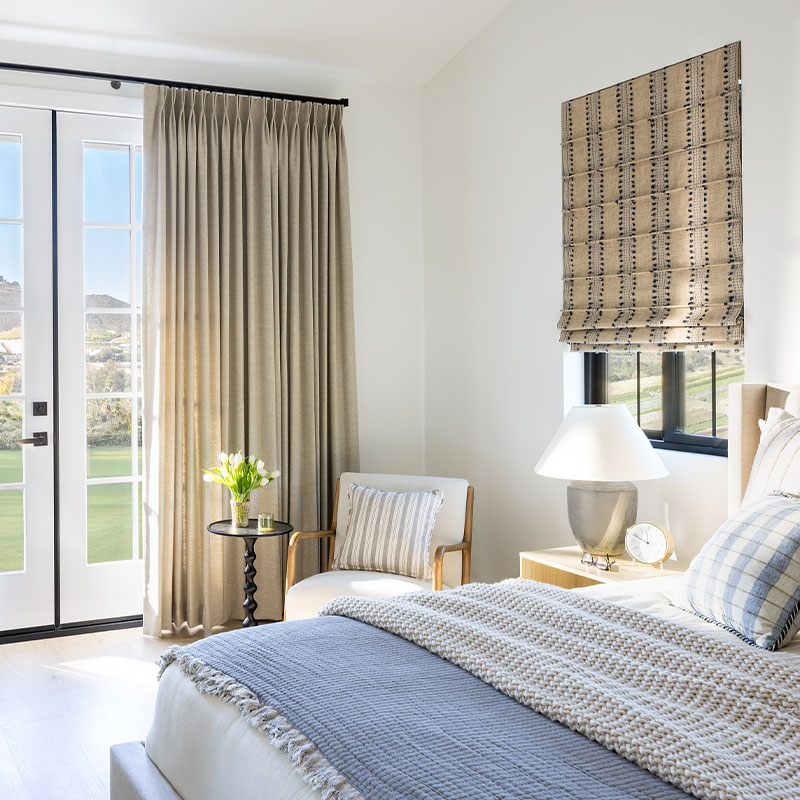Two Finger Pinch Pleat Drapery and Front Fold Roman Shade in a sunny bedroom.