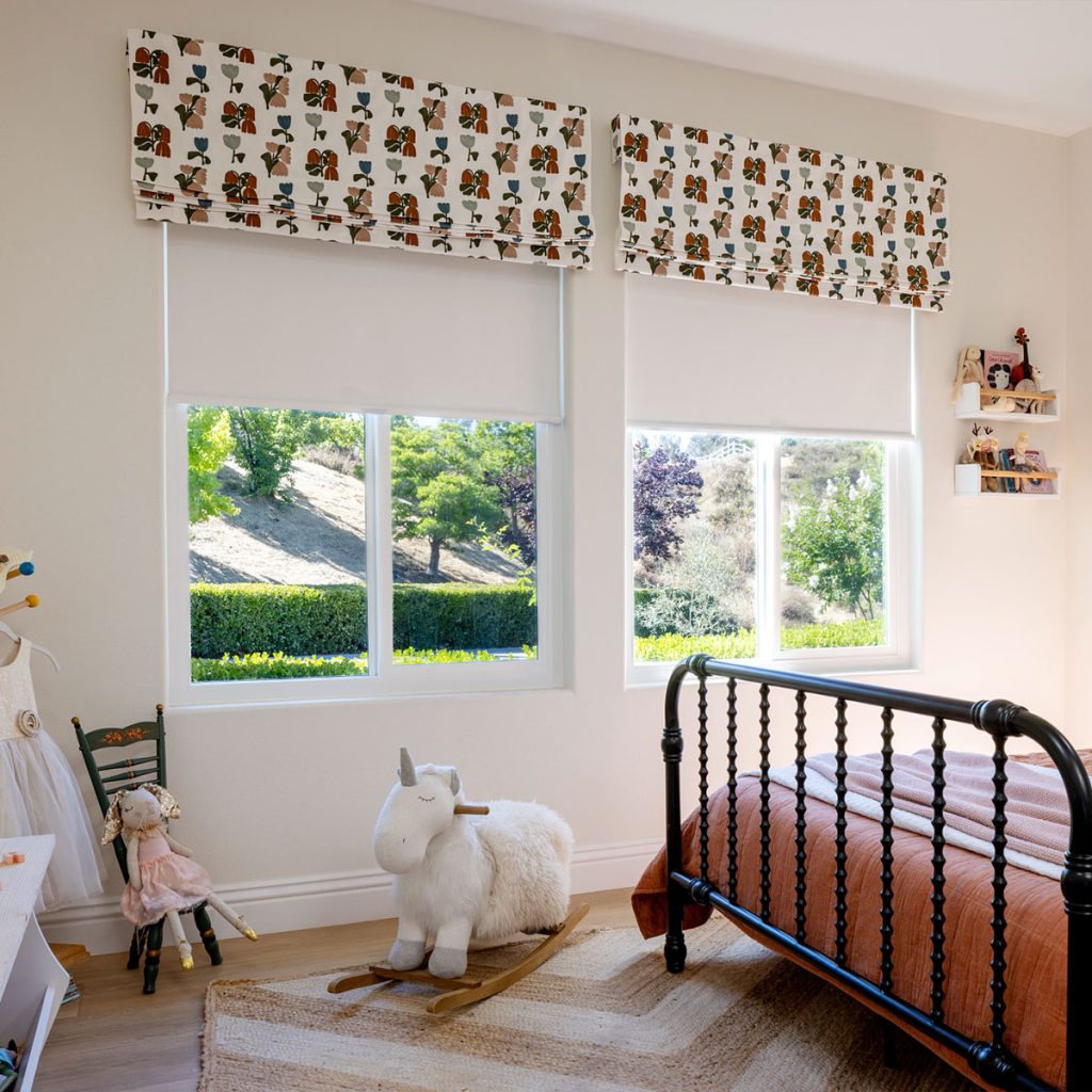 A girl's bedroom featuring two windows with Flat Faux Romans in a large scale embroidery pattern.