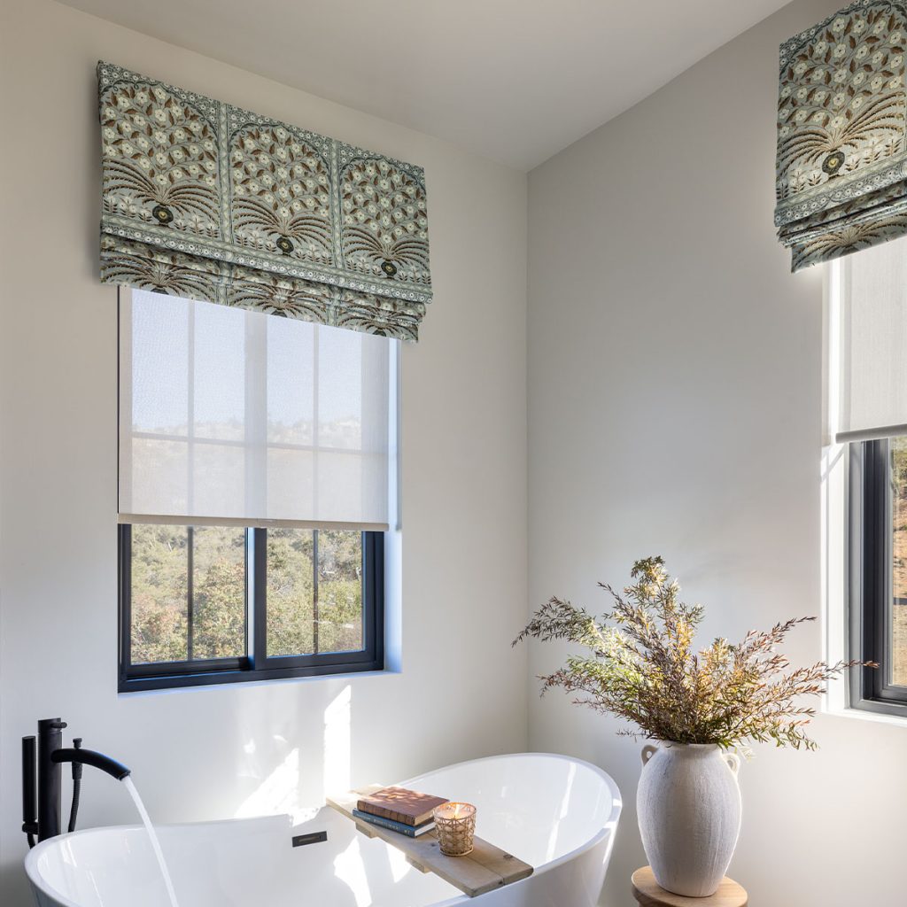 An elegant bathtub beneath windows featuring Flat Faux Romans in a neutral-toned intricate archtecturally inspired pattern.