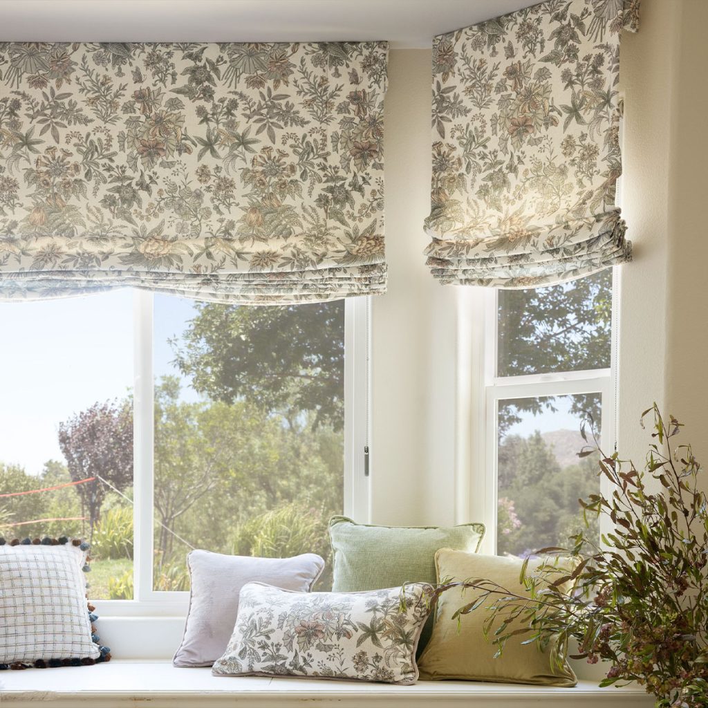 A bay window with cozy bench seating featuring Faux Soft Romans in a neutral-colored large scale floral motif.
