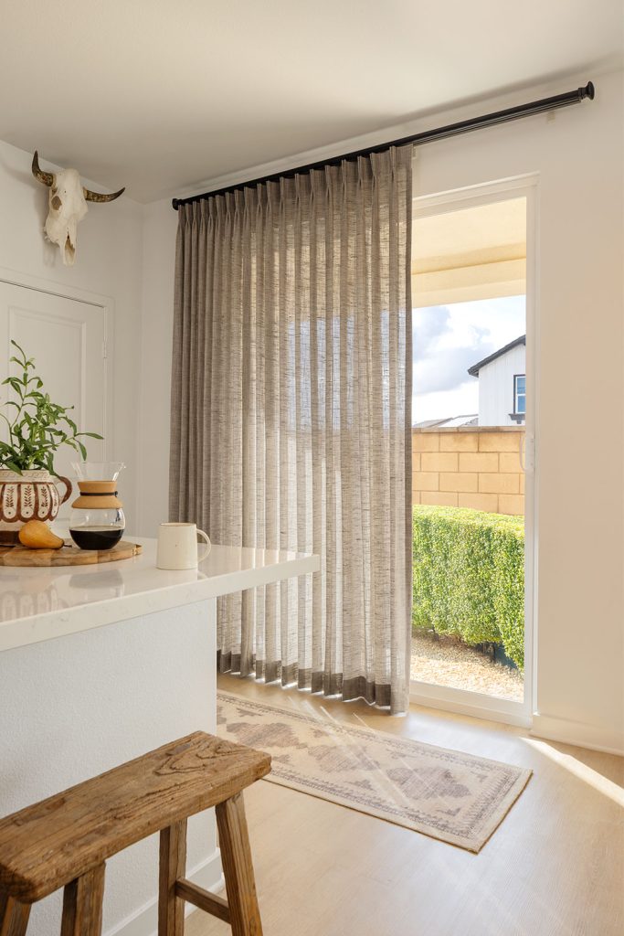 A kitchen counter next to a sliding glass door with floor to ceiling sheer Two Finger Pinch Pleat drapery.