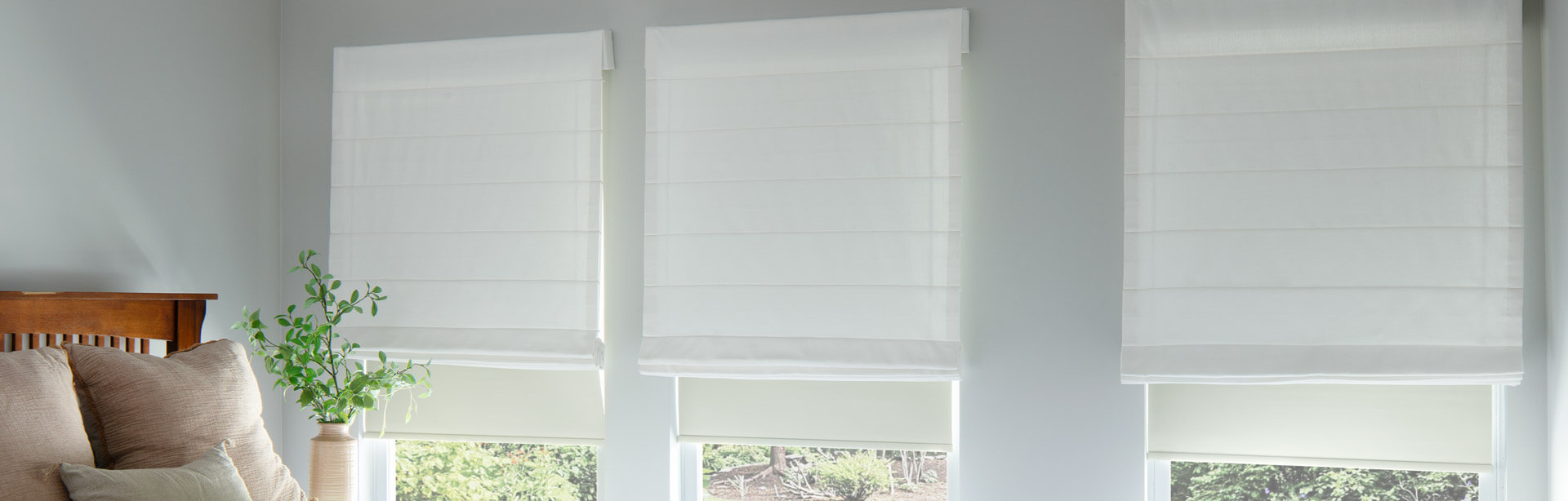 Three windows featuring white Soft Roman Shades over white roller shades.