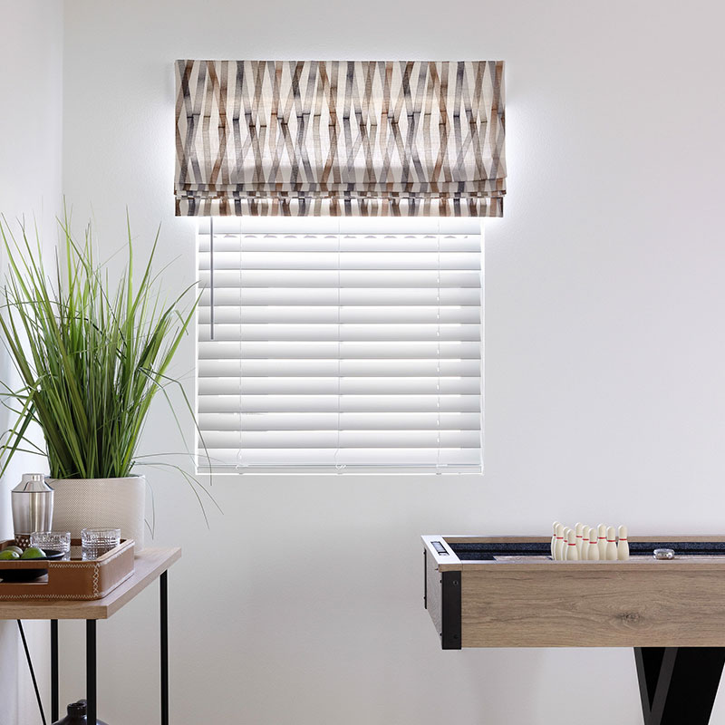 A Flat Faux Roman in an embroidered vertical pattern over a window in a game room.