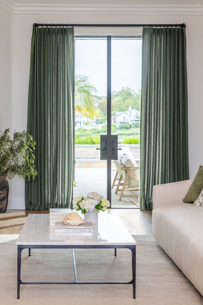 A living room in light neutrals and dark green accents featuring French doors with Single Pleat EZ Panels in dark green on black drapery hardware.