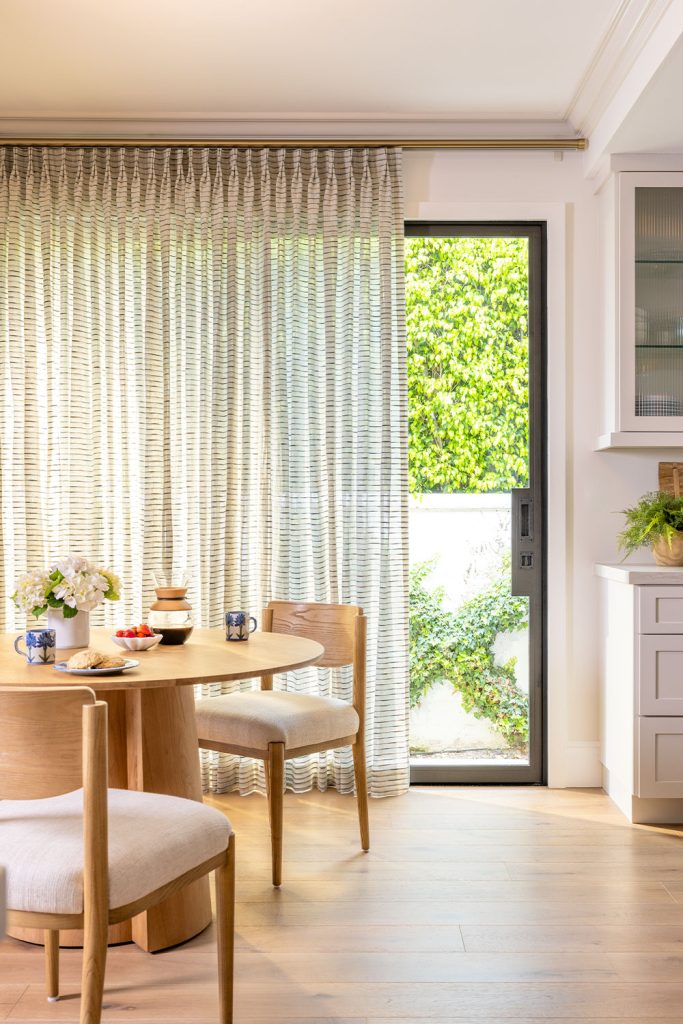 A kitchen nook featuring a sliding glass door with sheer horzontal striped neutral drapery.