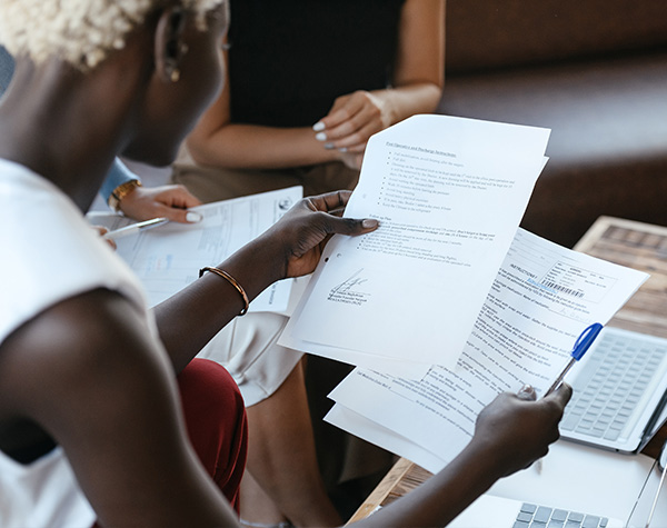 A woman reviews paperwork while holding a pen.