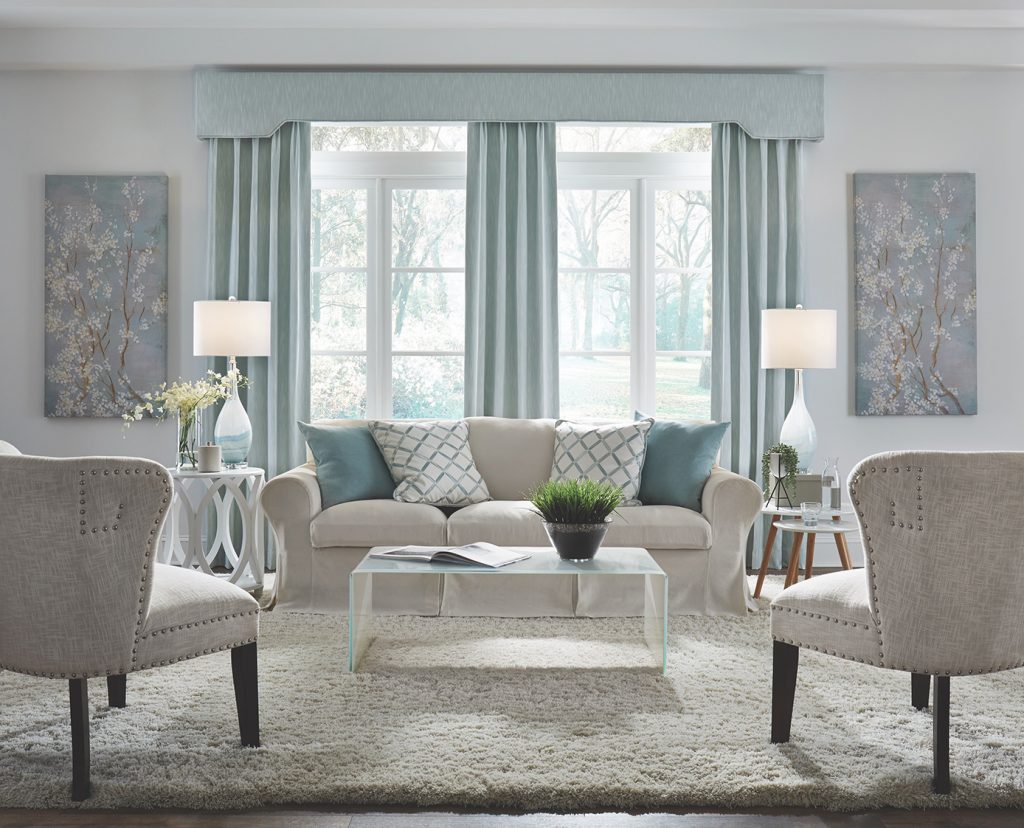 A living room that feels large and open in whites, light neutrals and pale blues.